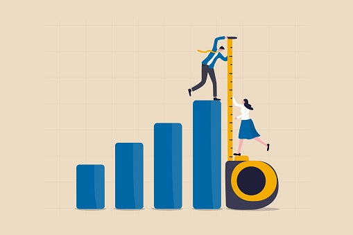 Business benchmark measurement, KPI, key performance indicator to evaluate success, improvement or business growth concept, businessman and woman help using measuring tape to measure bar graph.