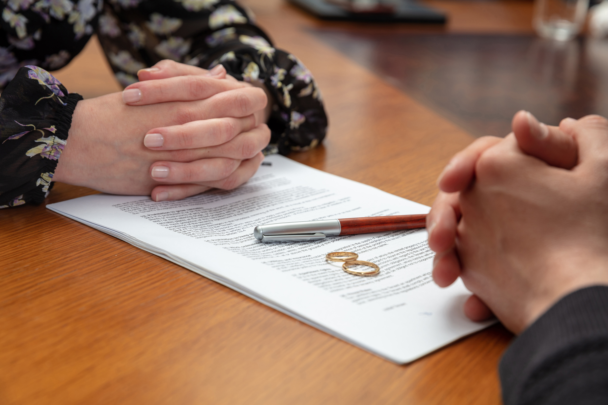 Divorce signature, marriage dissolution document. Wedding ring and agreement on lawyer office table